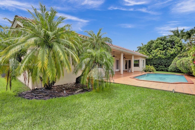 view of swimming pool with ceiling fan, a yard, and a patio