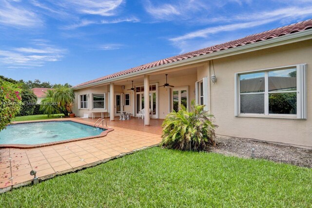 view of swimming pool with ceiling fan, a patio, and a lawn