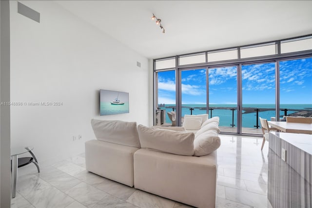 tiled living room with a water view, expansive windows, and rail lighting