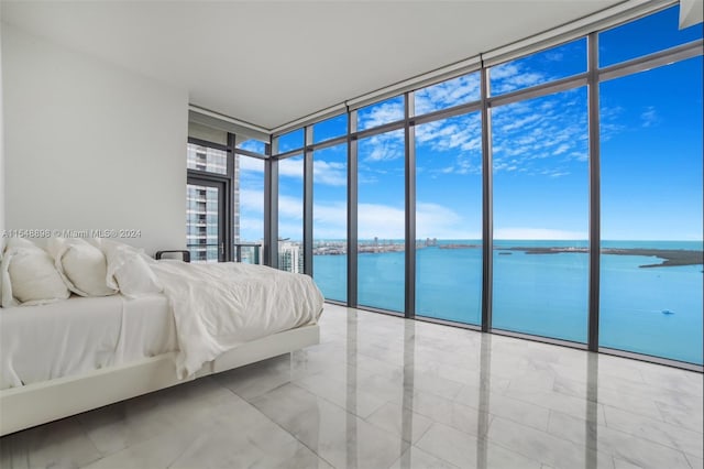 unfurnished bedroom featuring floor to ceiling windows, a water view, and light tile floors