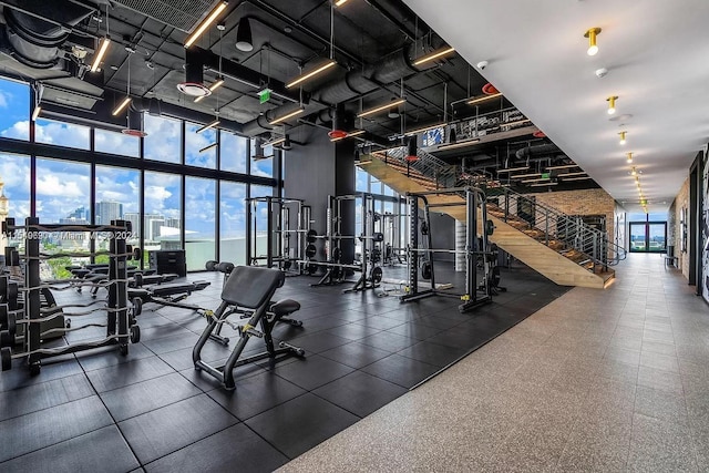 gym with expansive windows, a towering ceiling, and dark tile flooring