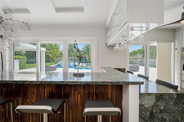 kitchen with stone countertops, white cabinetry, and a wealth of natural light