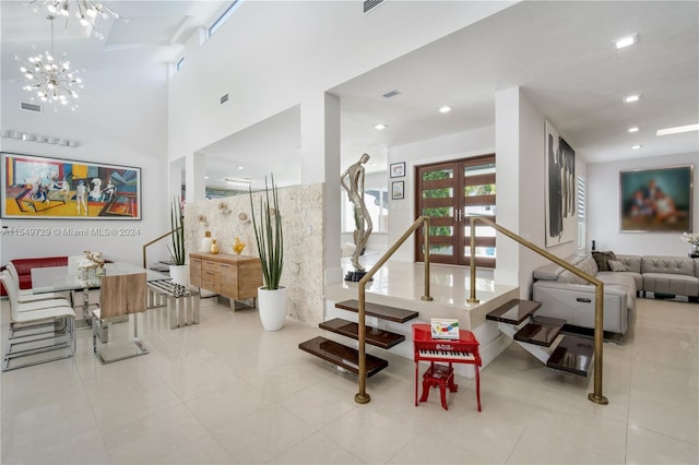 interior space featuring french doors, a towering ceiling, an inviting chandelier, and light tile floors