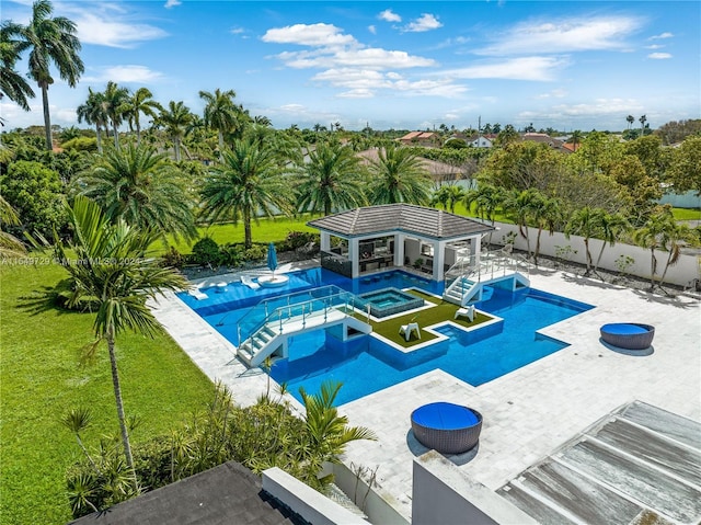 view of swimming pool with a patio area, a lawn, and an in ground hot tub