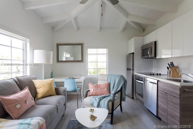 interior space with hardwood / wood-style flooring, vaulted ceiling with beams, ceiling fan, and sink