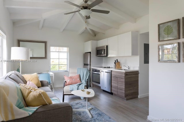 living room featuring light hardwood / wood-style floors, ceiling fan, sink, and lofted ceiling with beams