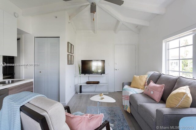 living room featuring dark wood-type flooring, ceiling fan, vaulted ceiling with beams, and sink