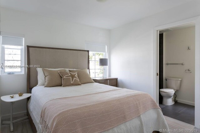 bedroom with ensuite bath and dark hardwood / wood-style flooring