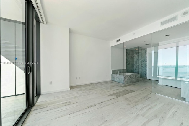 empty room with floor to ceiling windows and light hardwood / wood-style flooring