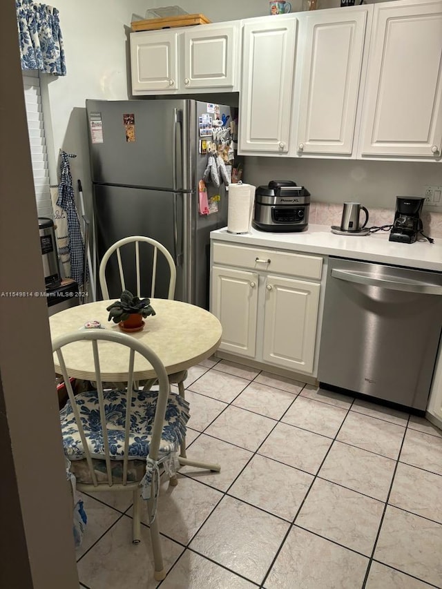 kitchen featuring light tile flooring, appliances with stainless steel finishes, and white cabinetry