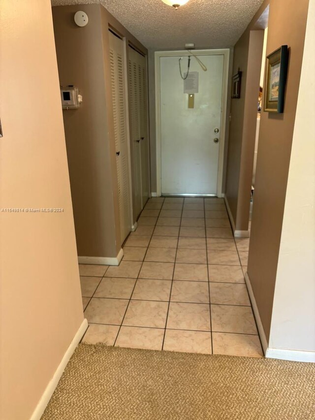 hall featuring light tile floors and a textured ceiling