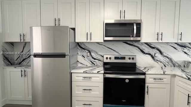 kitchen with tasteful backsplash, light stone counters, white cabinets, and stainless steel appliances