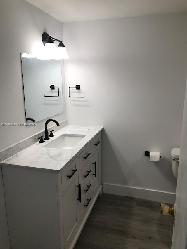 bathroom with hardwood / wood-style floors, vanity, and toilet