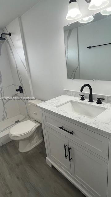 bathroom featuring toilet, hardwood / wood-style floors, vanity, and walk in shower