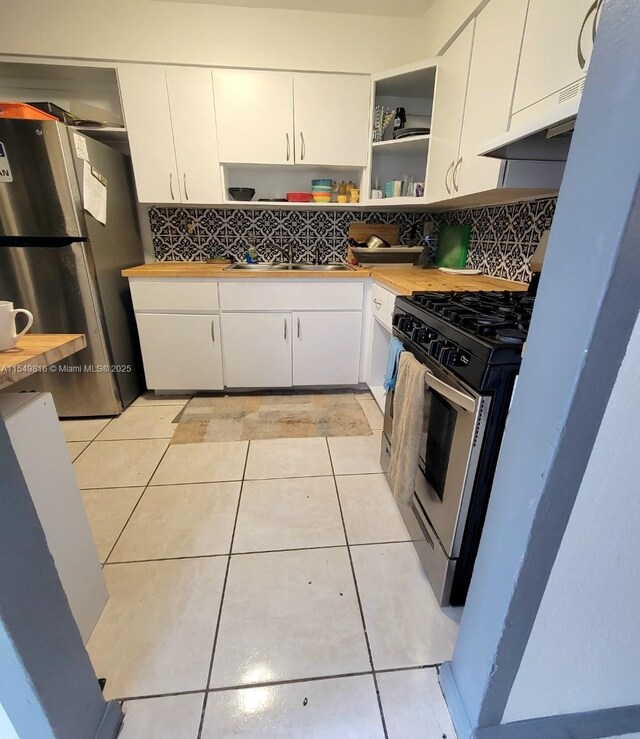 kitchen with tasteful backsplash, appliances with stainless steel finishes, white cabinets, and light tile floors