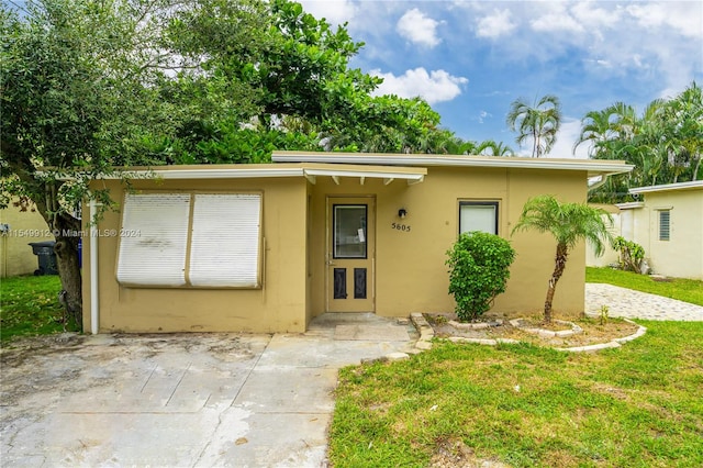 single story home featuring a front lawn and a patio area