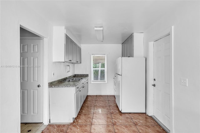 kitchen featuring white fridge, sink, light tile patterned floors, and gray cabinetry