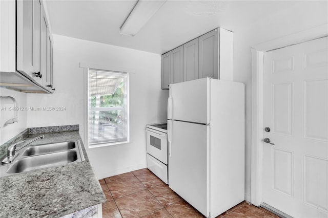 kitchen with light tile patterned floors, light countertops, white appliances, and a sink