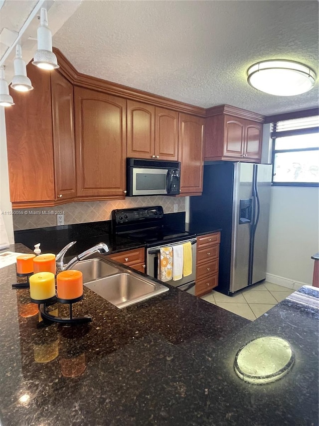 kitchen with backsplash, black appliances, sink, dark stone counters, and pendant lighting