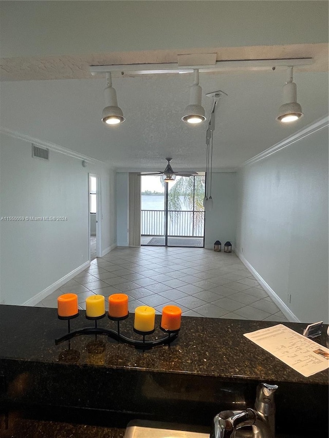 kitchen featuring tile floors, dark stone countertops, ornamental molding, and rail lighting