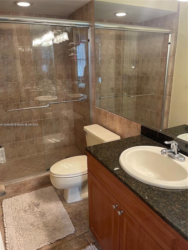 bathroom featuring toilet, a shower with door, tile flooring, and vanity