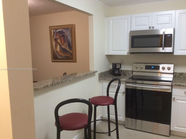 kitchen with white cabinetry, appliances with stainless steel finishes, and light stone countertops