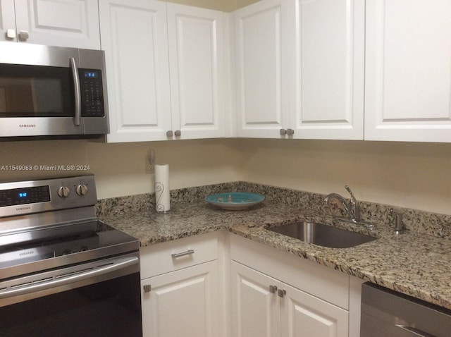 kitchen with white cabinets, appliances with stainless steel finishes, and light stone counters