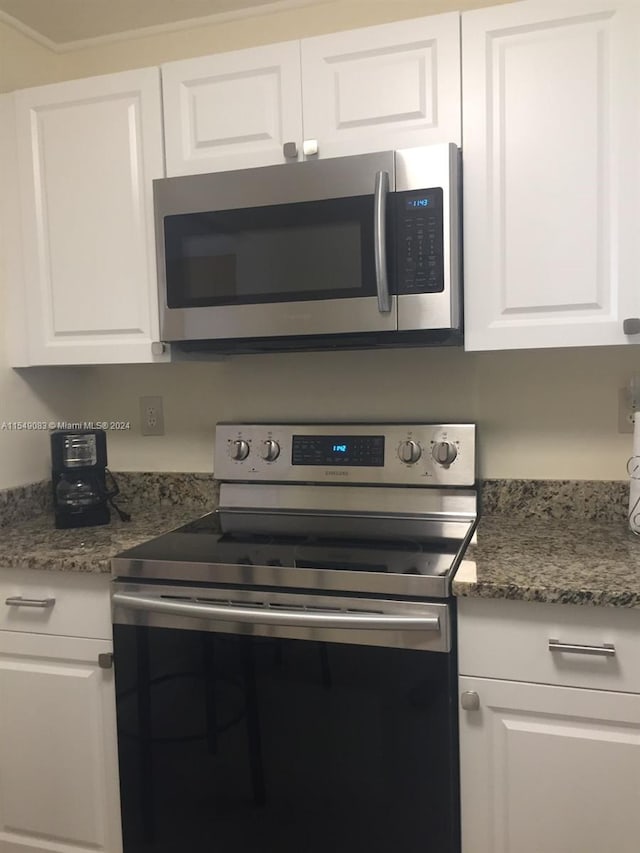 kitchen with dark stone counters, white cabinetry, and stainless steel appliances