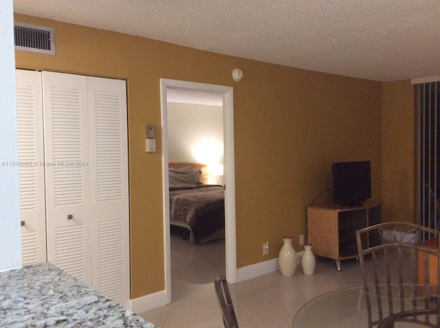 bedroom with a closet, a textured ceiling, and light tile floors