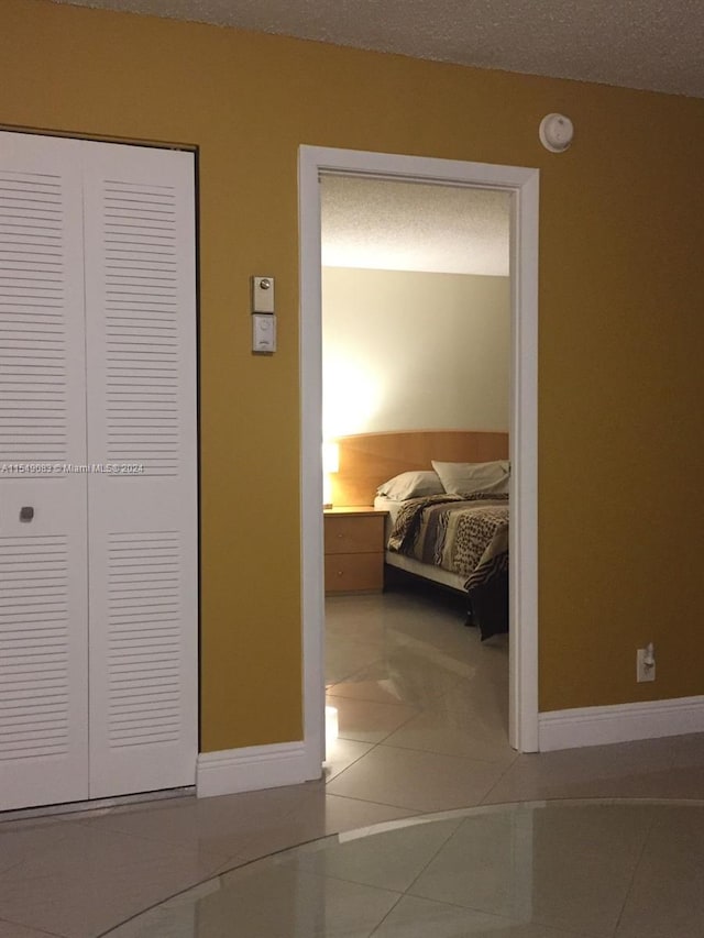 unfurnished bedroom featuring a closet, light tile floors, and a textured ceiling