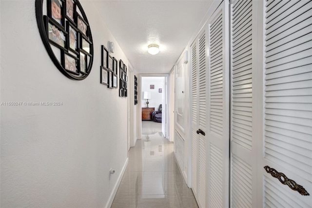 hall featuring a textured ceiling and light tile floors