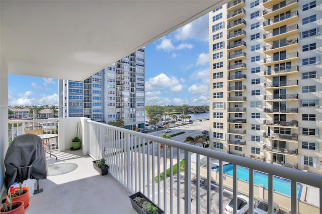 balcony with a water view and a fenced in pool