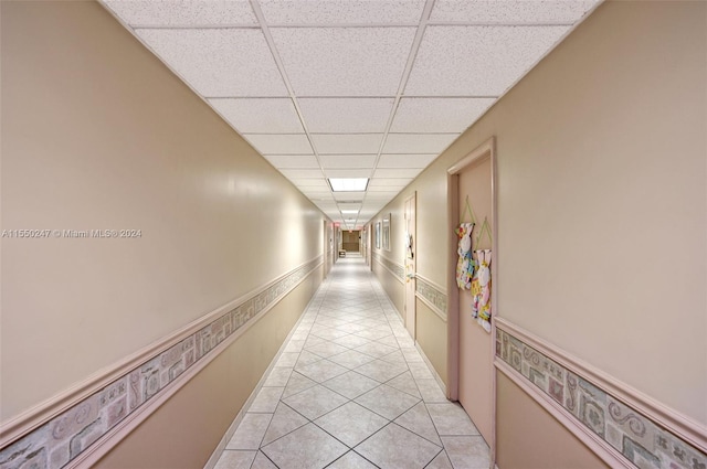 hall featuring a drop ceiling and light tile floors