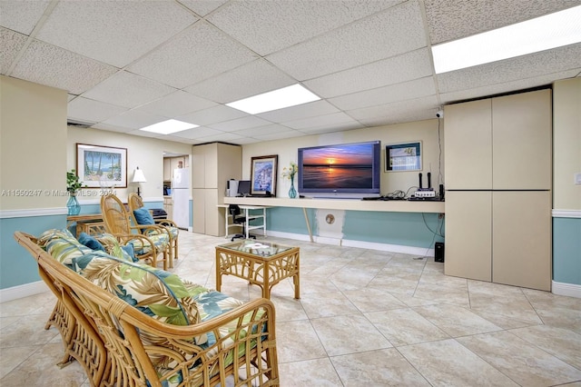 tiled living room featuring built in desk and a drop ceiling