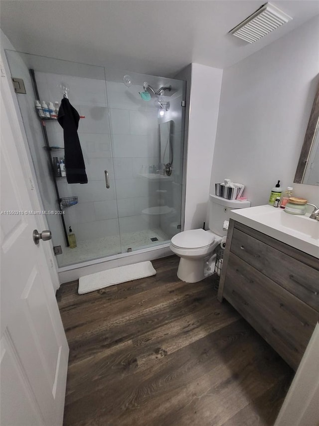 bathroom featuring vanity, a shower with shower door, wood-type flooring, and toilet