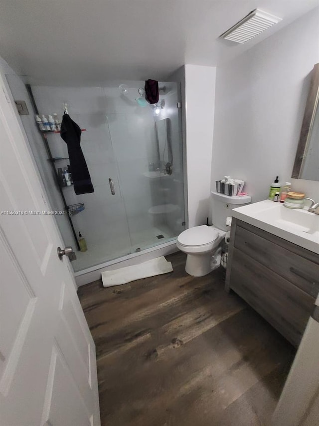 bathroom with wood-type flooring, an enclosed shower, toilet, and vanity