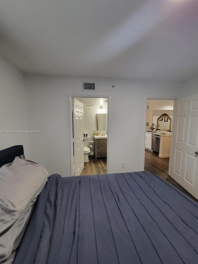 bedroom featuring ensuite bathroom and dark hardwood / wood-style floors