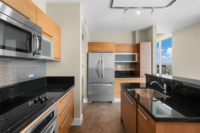 kitchen with dark tile floors, backsplash, appliances with stainless steel finishes, sink, and track lighting