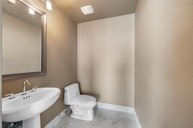 bathroom featuring toilet, tile flooring, and sink