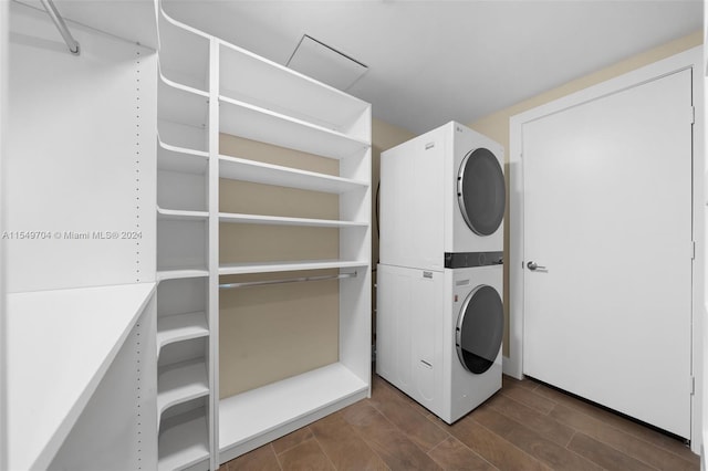 washroom with dark wood-type flooring and stacked washer / dryer