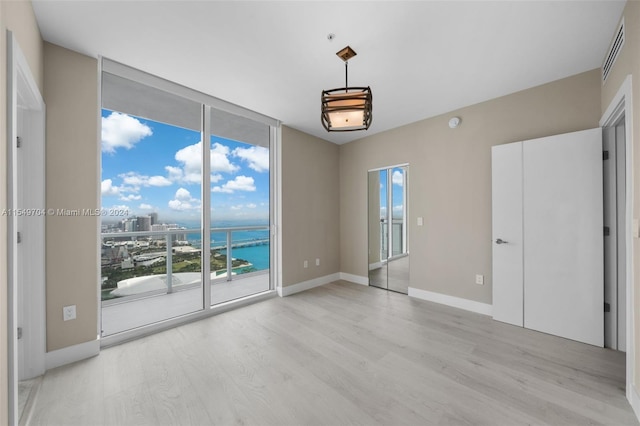 spare room with a water view and light hardwood / wood-style flooring