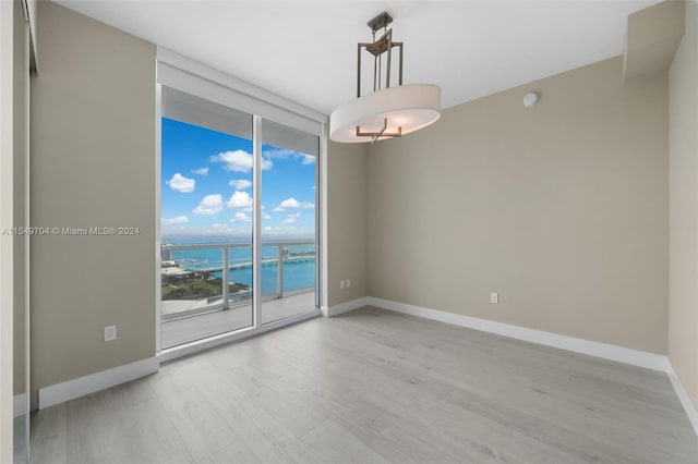 spare room featuring a water view, light hardwood / wood-style flooring, and floor to ceiling windows