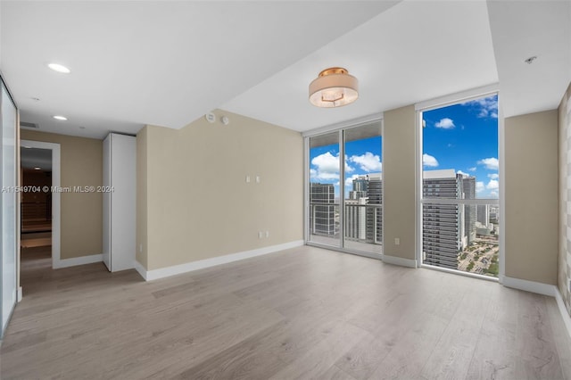 unfurnished room featuring floor to ceiling windows and light hardwood / wood-style floors