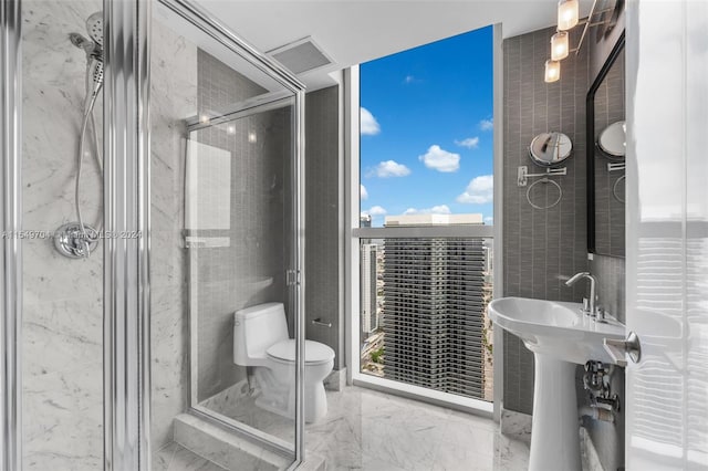 bathroom featuring a shower with door, toilet, tile flooring, and tile walls