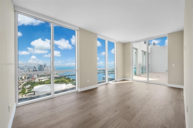 spare room featuring a water view, floor to ceiling windows, and hardwood / wood-style flooring