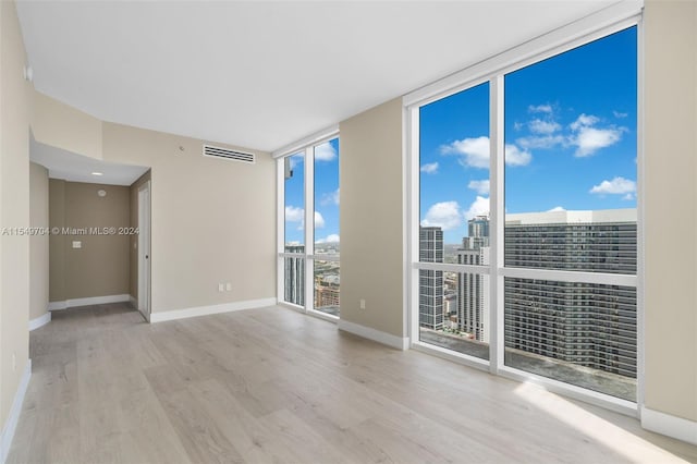 unfurnished room with floor to ceiling windows and light hardwood / wood-style flooring