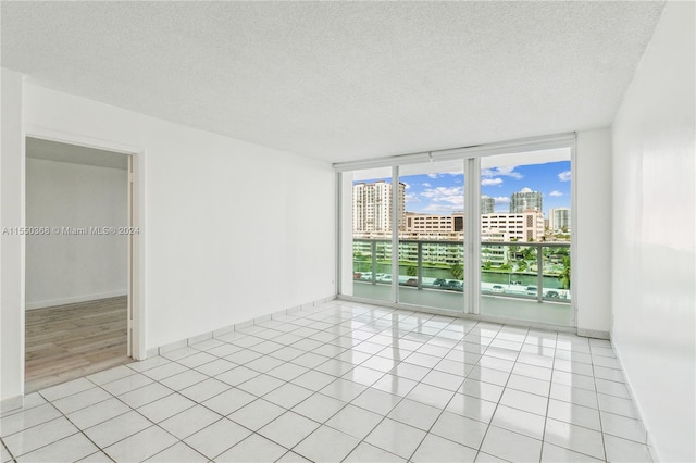 tiled empty room featuring a textured ceiling