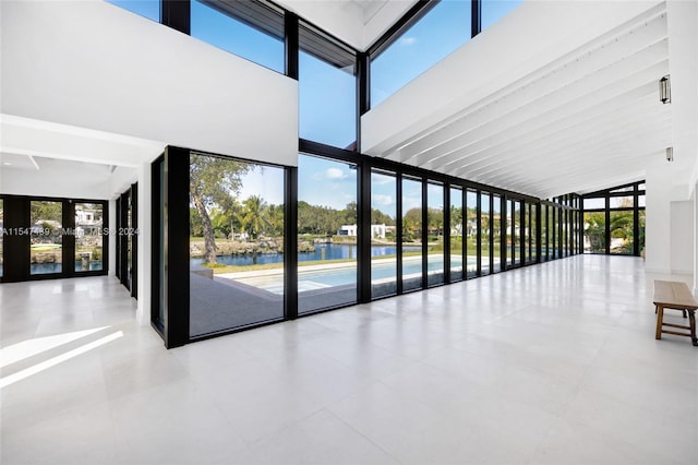 interior space featuring beam ceiling, tile floors, french doors, and a water view