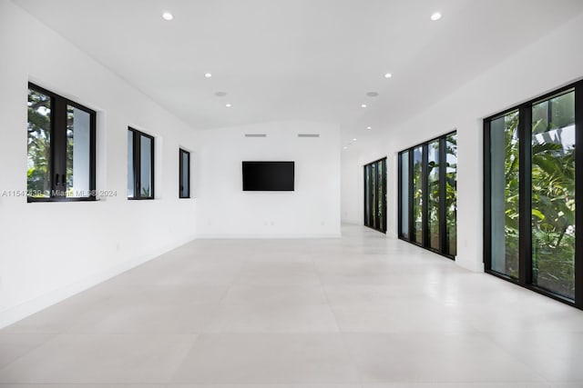 spare room featuring light tile flooring and vaulted ceiling