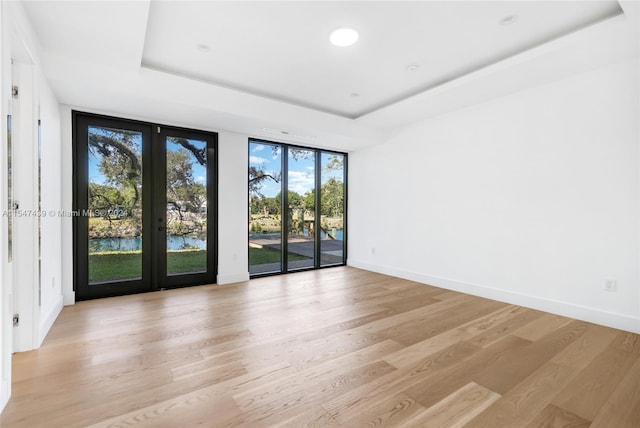 spare room with french doors, light wood-type flooring, and a wall of windows